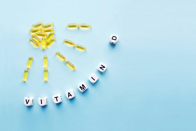 Yellow capsules in the form of the sun with rays and the word vitamin d Premium Photo