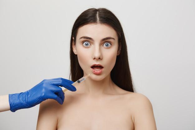 Shocked woman open mouth and stare worried while take bottox injection in lip Free Photo